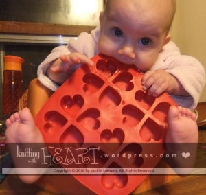 our teething sweetheart niece biting on a heart-shaped baking dish
